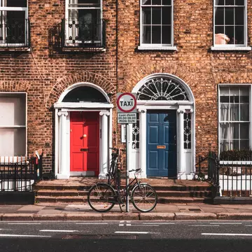 Brick buildings, with white trim; one has a red door, and the other has a blue door.