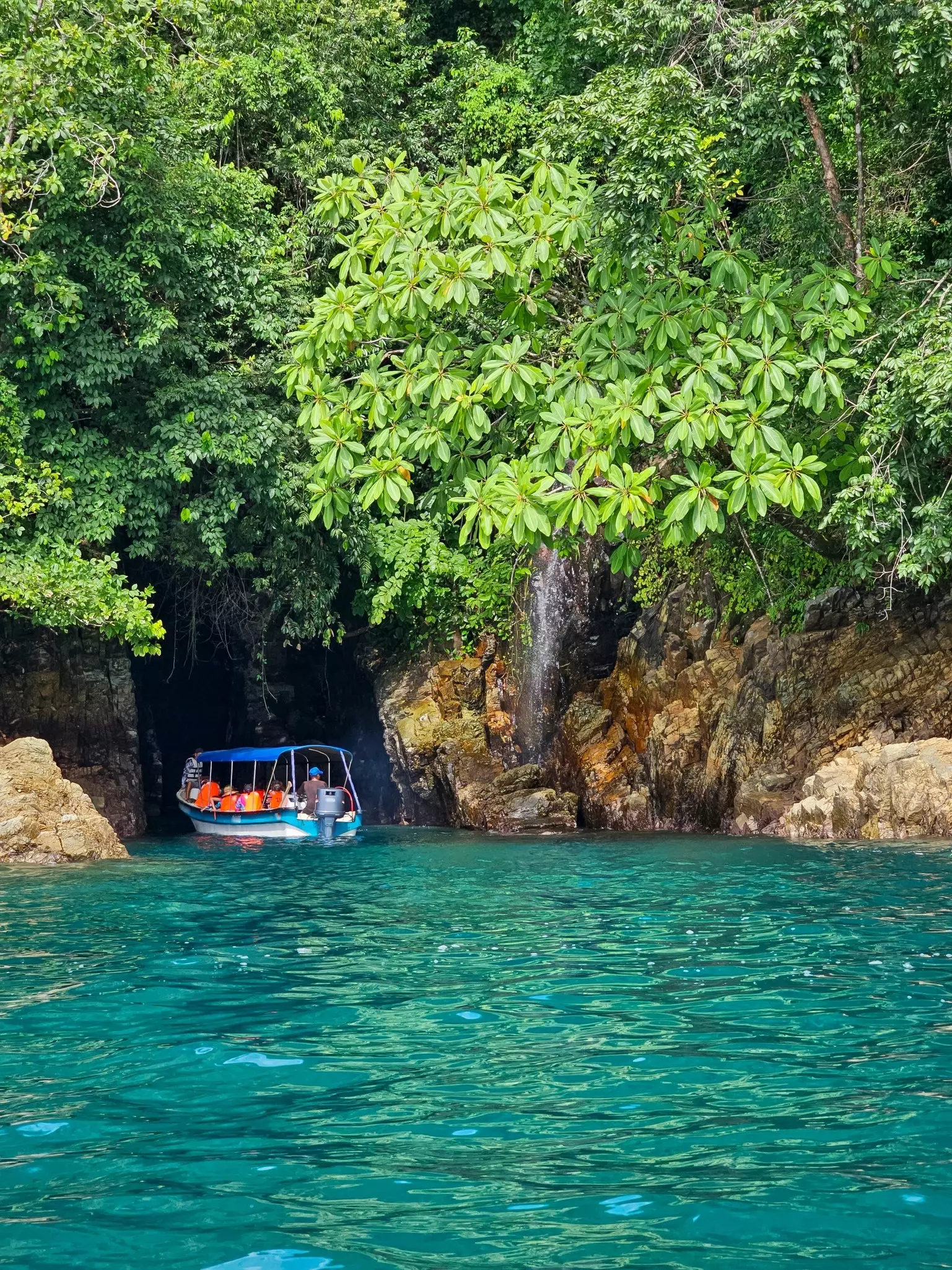 A tourist-laden boat sails between rocks an into an inlet surrounded by jungle in Coiba National Park, Panama