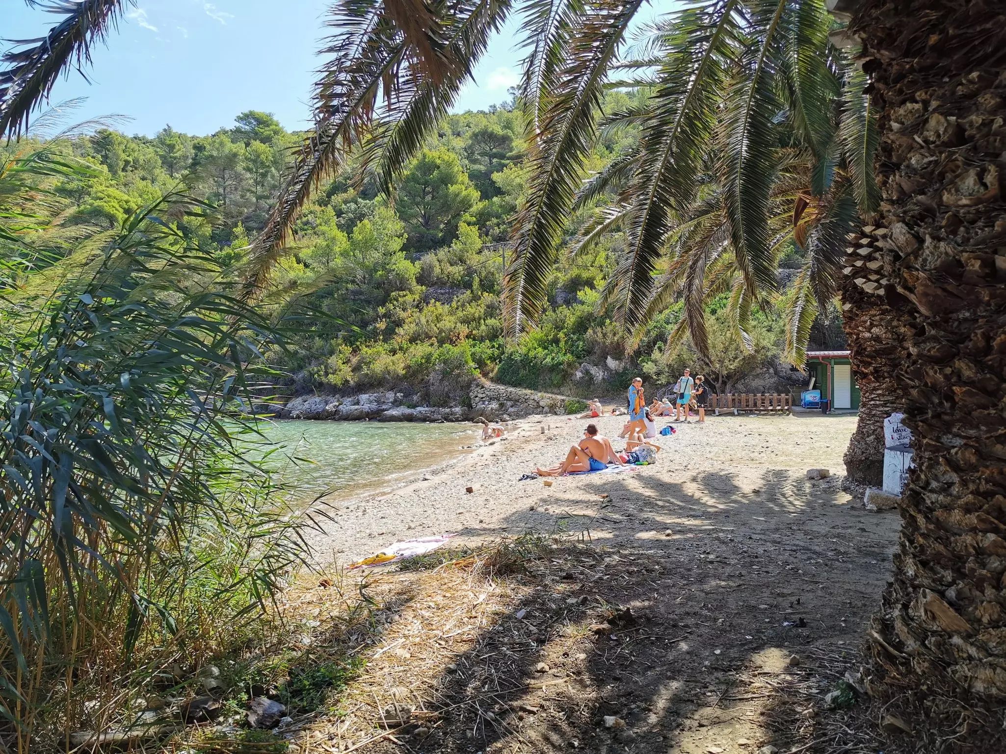 A small group of people relax on the rocky shore of Vis Island, Croatia.