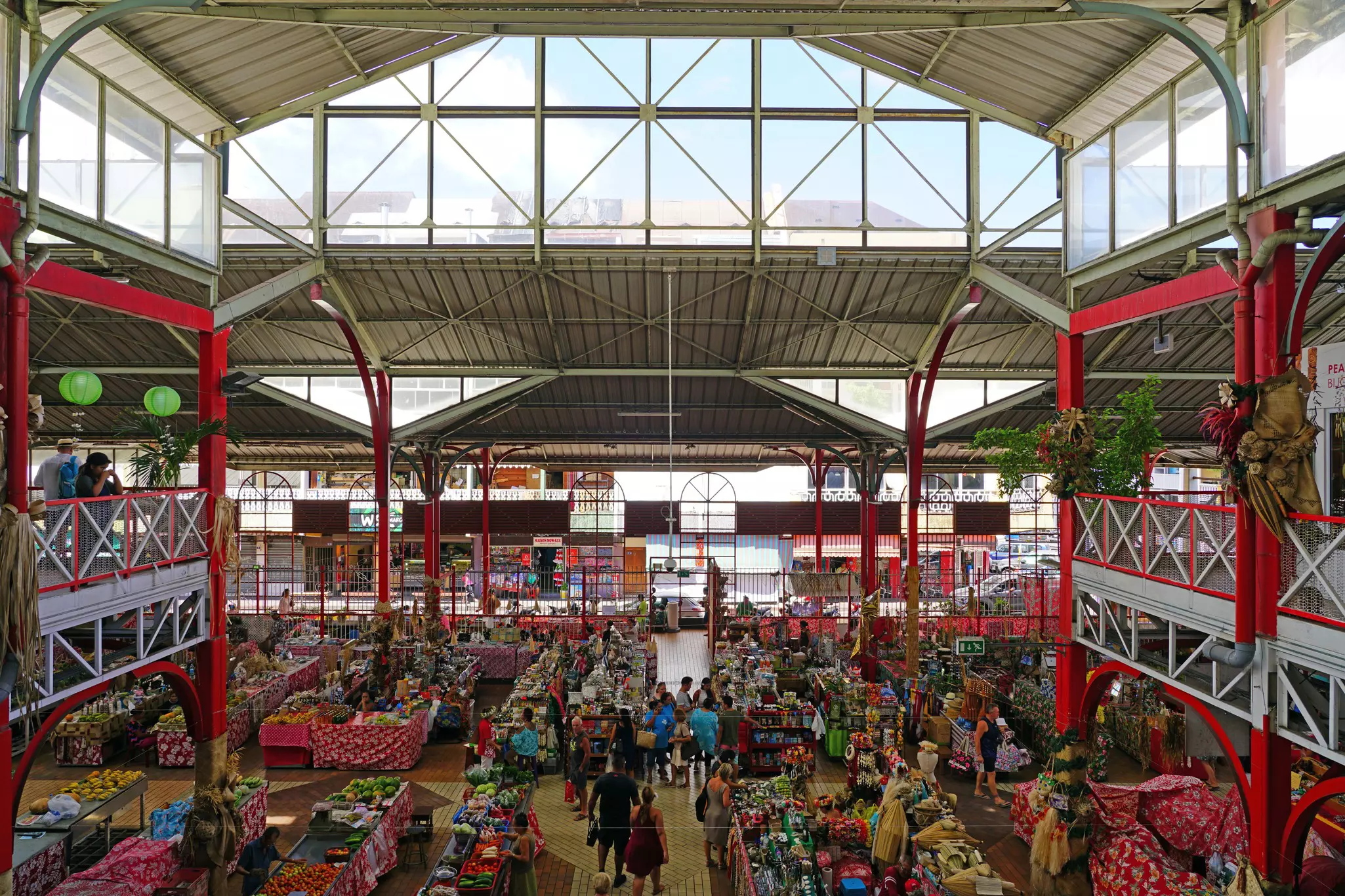 A busy covered market with vendors selling fresh food and souvenirs.