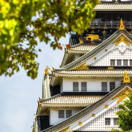 Trees frame a photo with a white tiered building detailed with gold