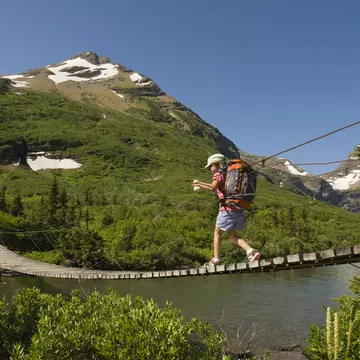 A young girl hikes over a suspension bridge in Glacier National Park, Montana.