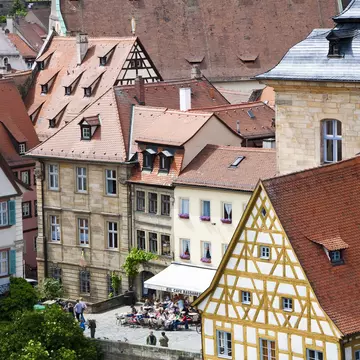 Red-tiled rooftops lead down to a city square where people are having a drink outside a cafe