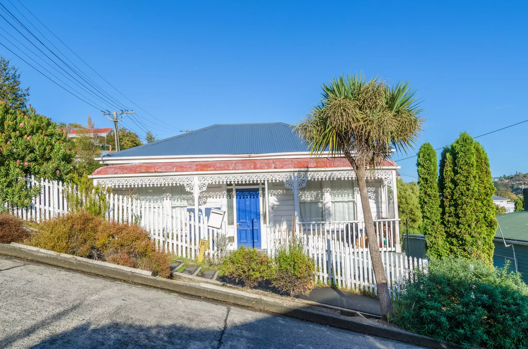 The frontage of a small single-story house on a street with a very large angle.