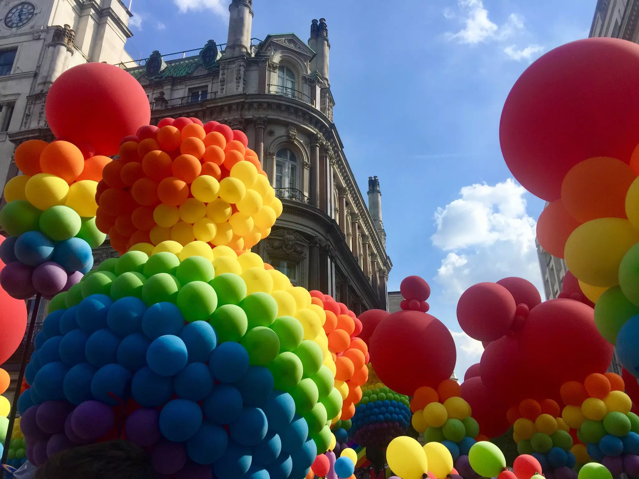 Rainbow color balloons in gay pride parade in London, with buildings in background.