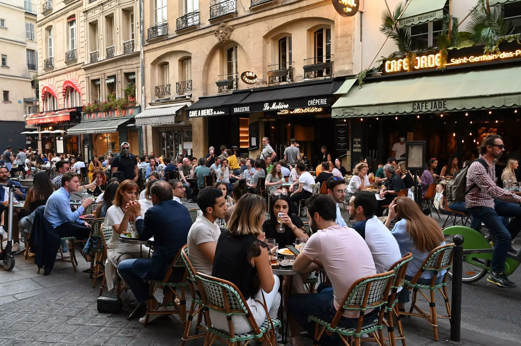 People eat and have drinks on restaurant and cafe terraces in Rue de Buci in Paris