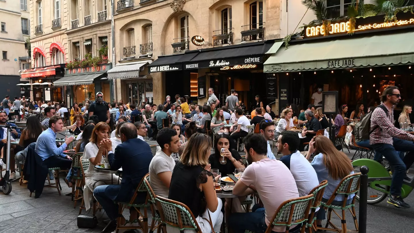 People eat and have drinks on restaurant and cafe terraces in Rue de Buci in Paris