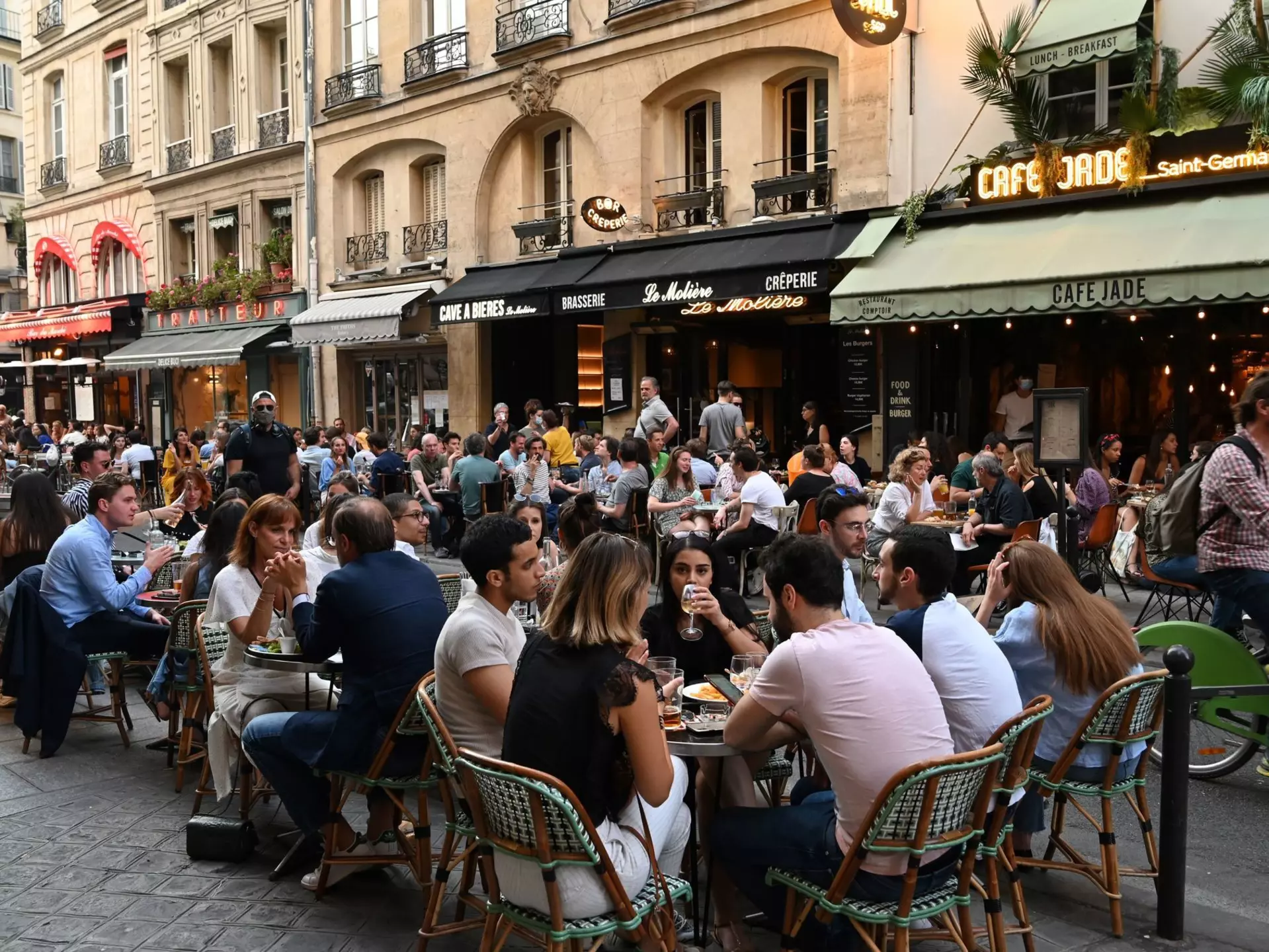 People eat and have drinks on restaurant and cafe terraces in Rue de Buci in Paris
