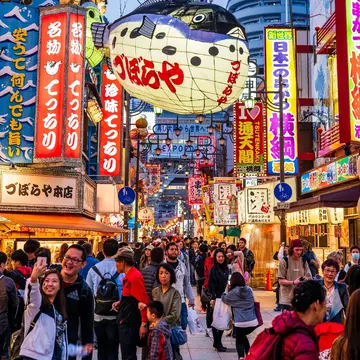 Shinsekai, Osaka, Japan. April 6 2019. Street view, crowded pedestrian precinct with the Tsutenkaku Tower towering over Shinsekai at blue hour. Illuminated Puffer fish lantern, Zuboraya. restaurant, License Type: media, Download Time: 2026-05-28T19:31:03.000Z, User: LP_NZhan, Editorial: true, purchase_order: 65050 - Digital Destinations and Articles, job: App Content, client: Lonely Planet App, other: Nadine Zhan