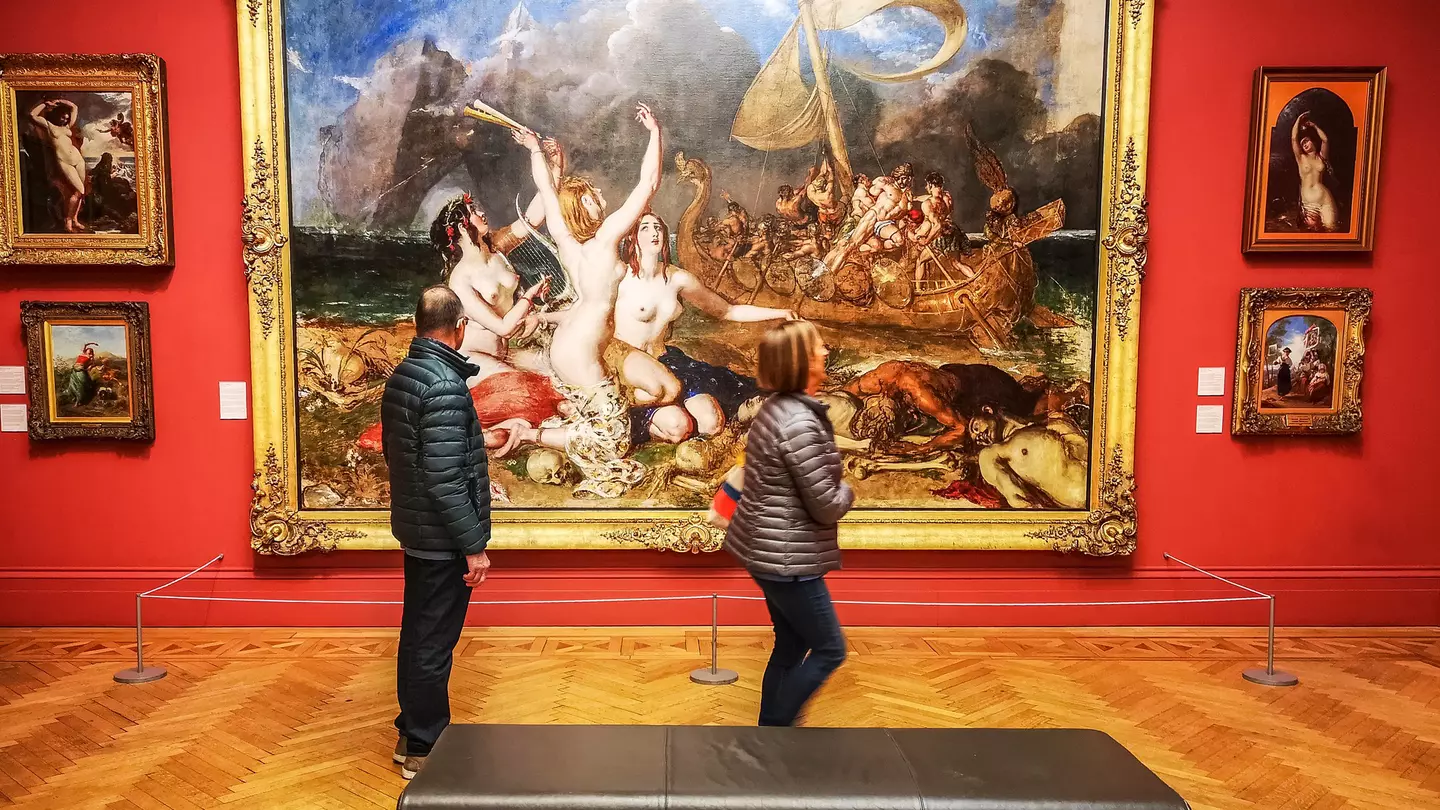 Visitors walk by paintings in the famous Manchester Art Gallery, Manchester, England, UK