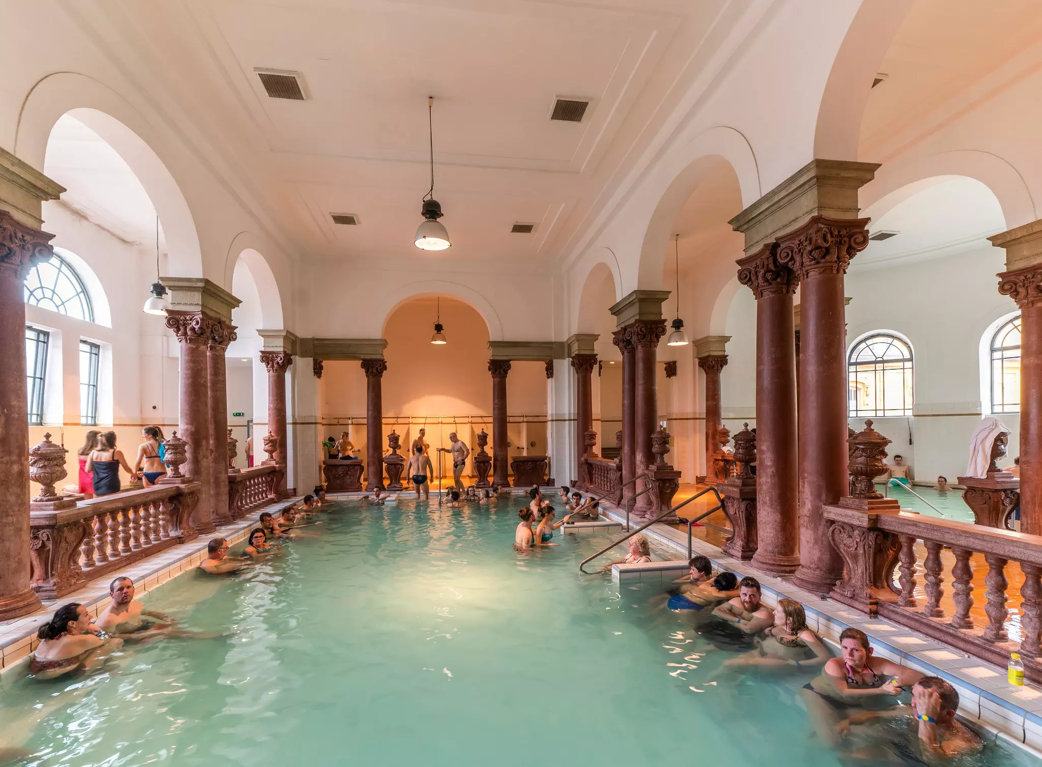 People soak in the waters or stand outside the pool at Szechenyi Baths in Budapest.