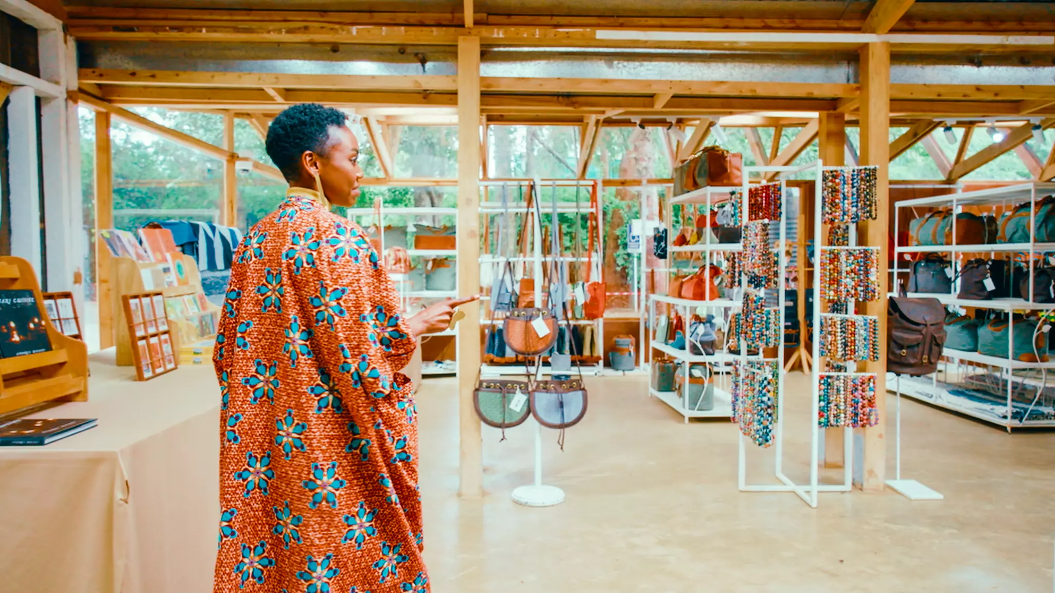 A woman wearing a printed tunic enters a store stocked with gifts and handicrafts.