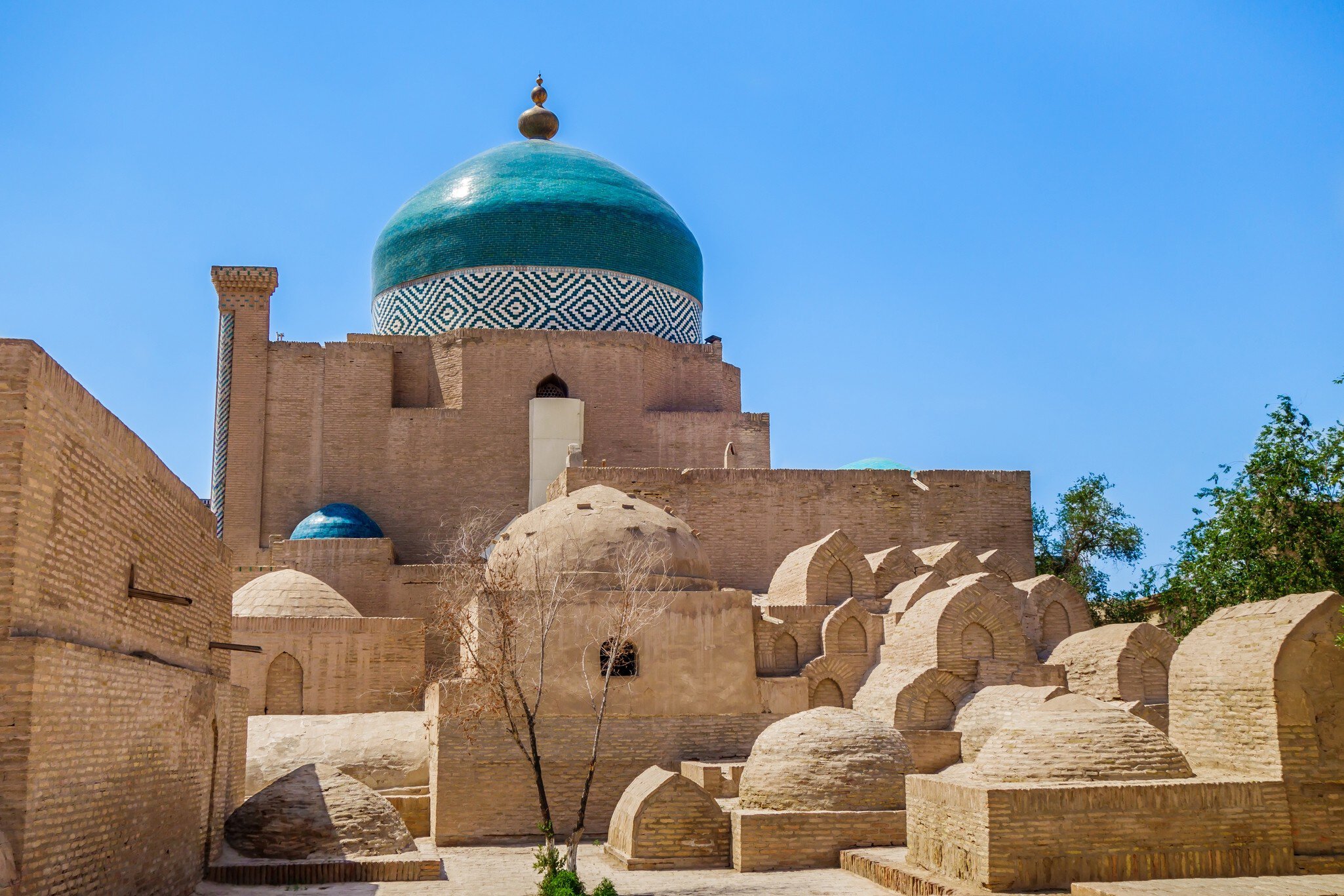 Mausoleum of Pahlavan Mahmoud, medieval poet and pahlevani champion. One of main historical sites in Khiva, Uzbekistan. Building is surrounded by small ancient graves from different centuries; Shutterstock ID 2083392193;
