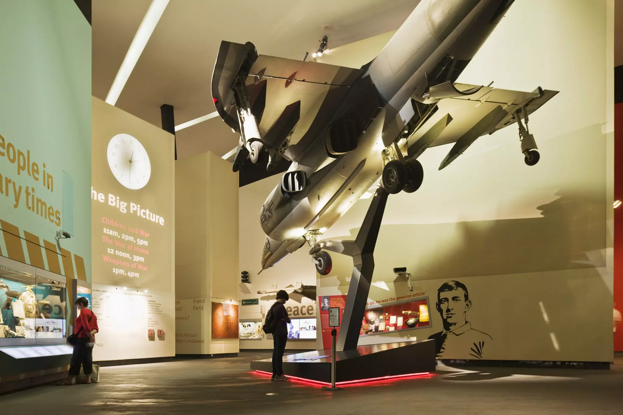 A museum display with a jet suspended above the ground pointing downwards. Two people are admiring the exhibits