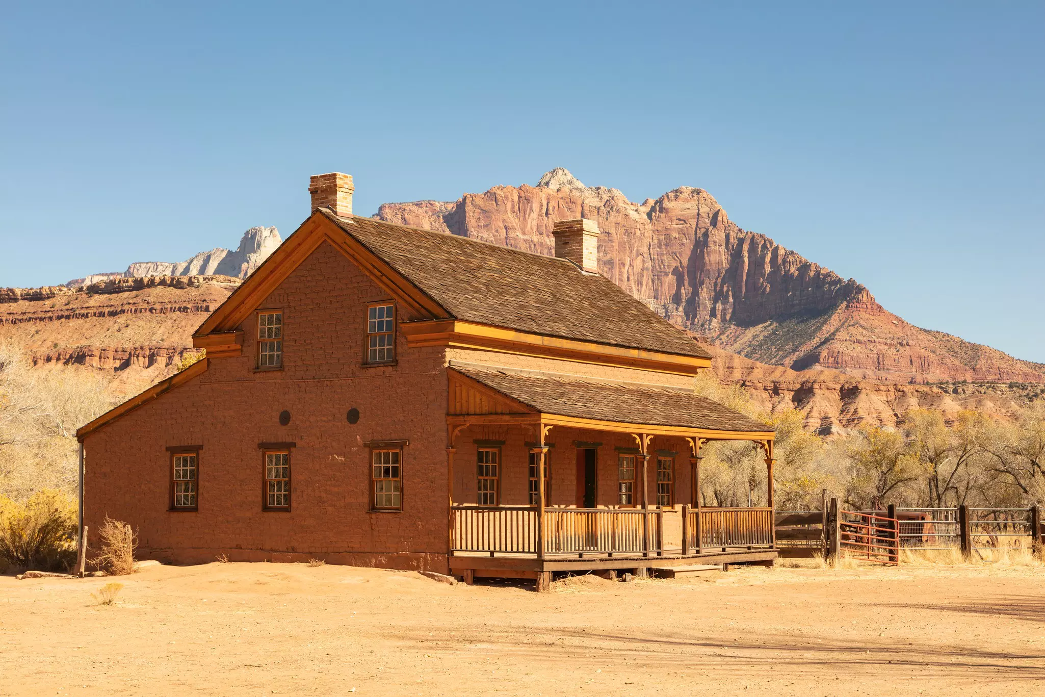 An abandoned house and picket fence against rock formations and a blue sky at Grafton ghost town, Utah