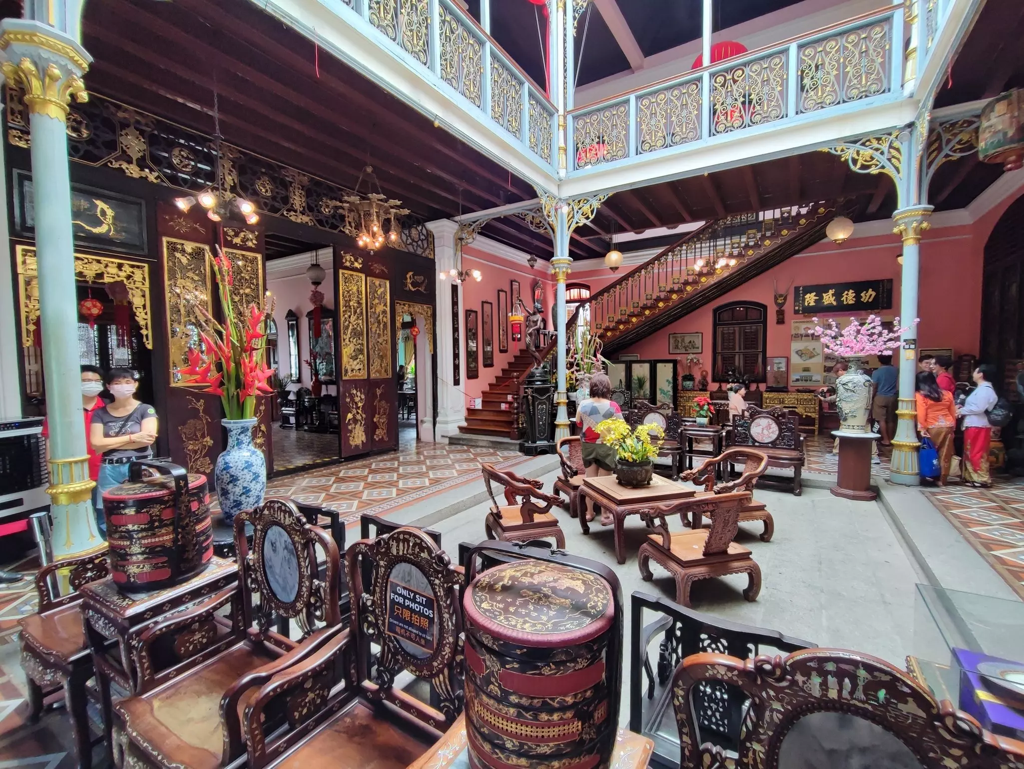 Historic colonial-era mansion interior with ornate wrought iron railings, wooden balconies, and spacious space in the main hall .