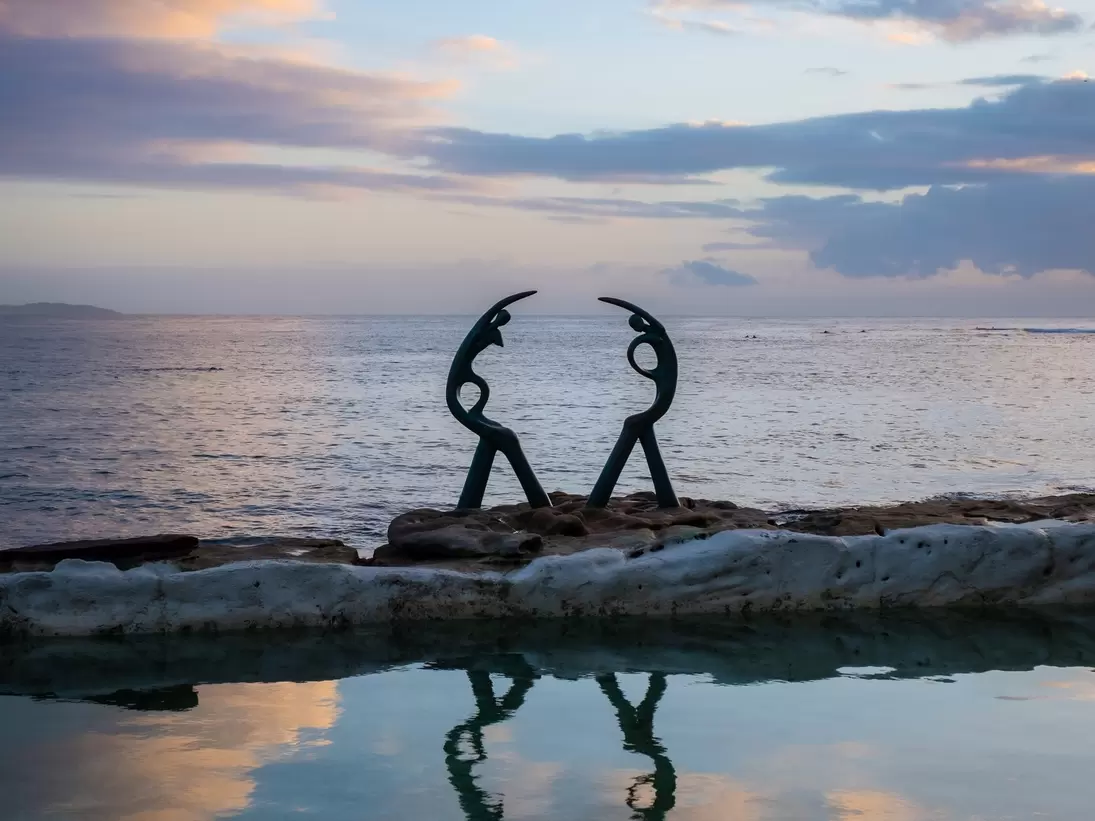 The Oceanides sculpture at Fairy Bower pool and beach, Manly, Sydney, Australia. Sunset reflection on water.