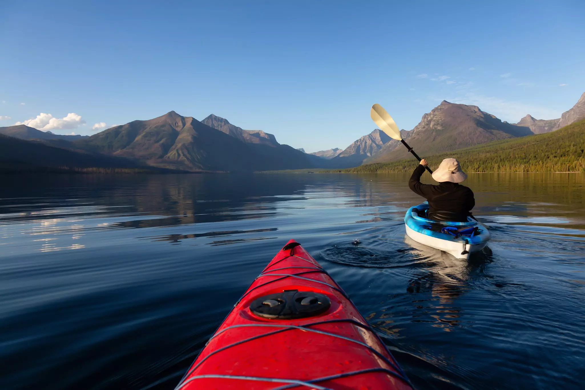 Man kayaking in Lake McDonald with the Rocky Mountains in the background in Glacier National Park, Montana, USA