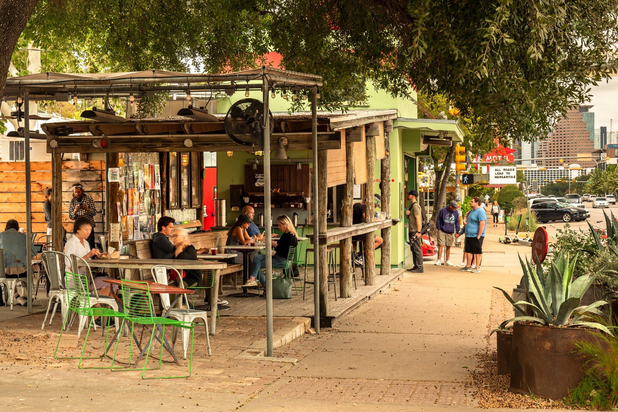 People eating at tables restaurant's outdoor terrace facing a sidewalk