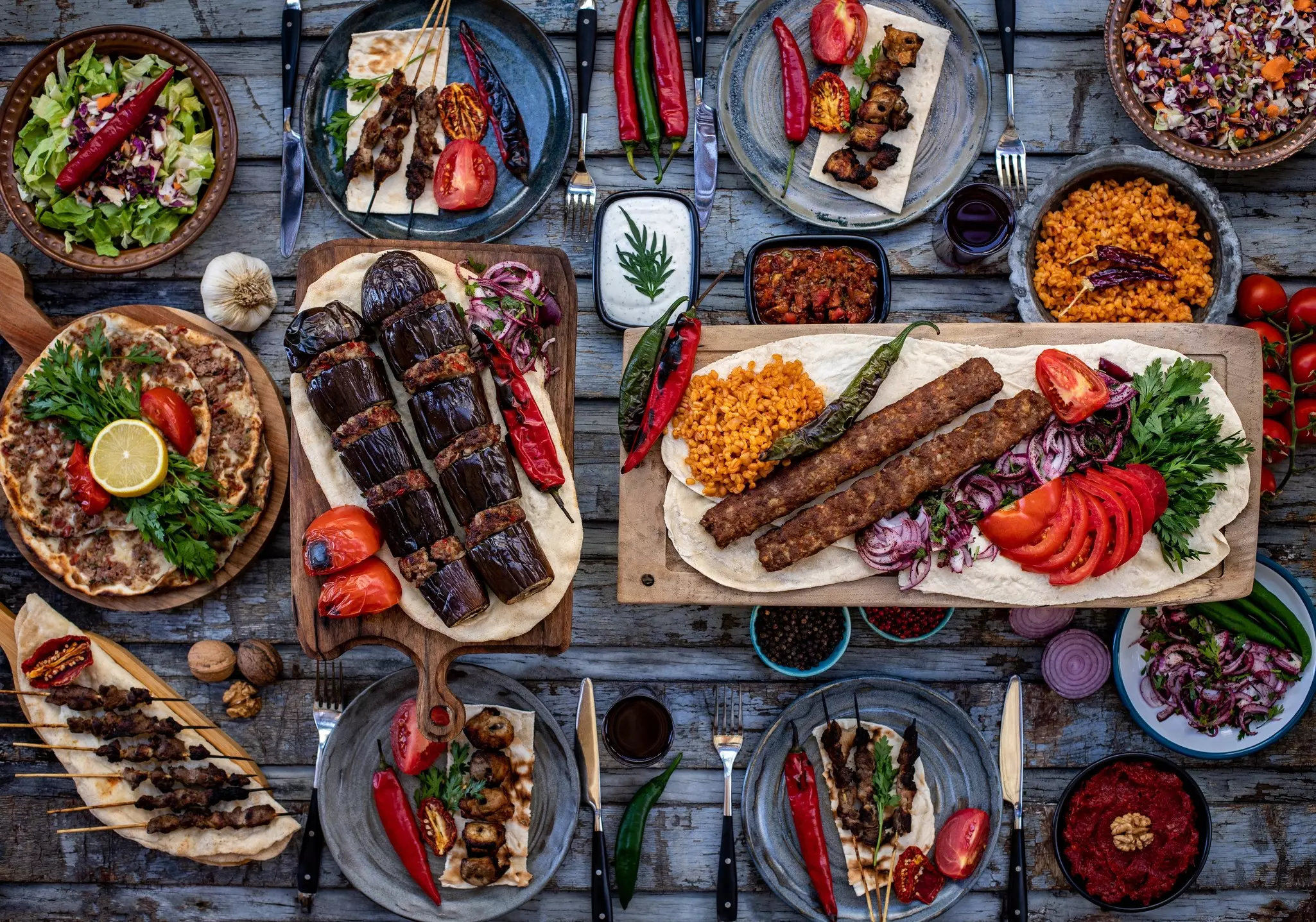 An overhead view of a table filled with dishes containing kebabs and other foods.