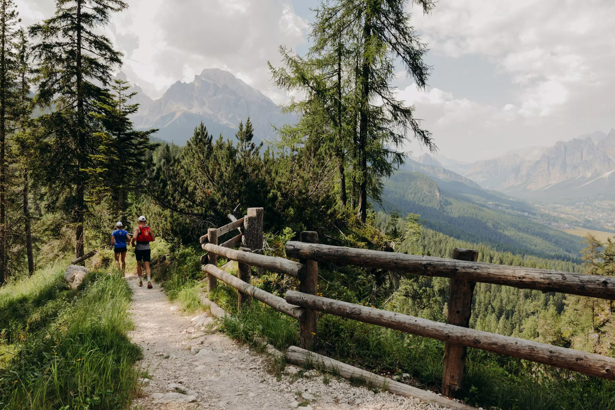 Hikers on a dirt trail lined with a wooden fence