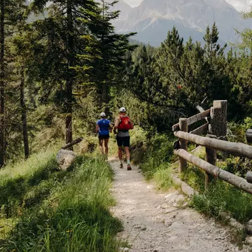Hikers on a dirt trail lined with a wooden fence
