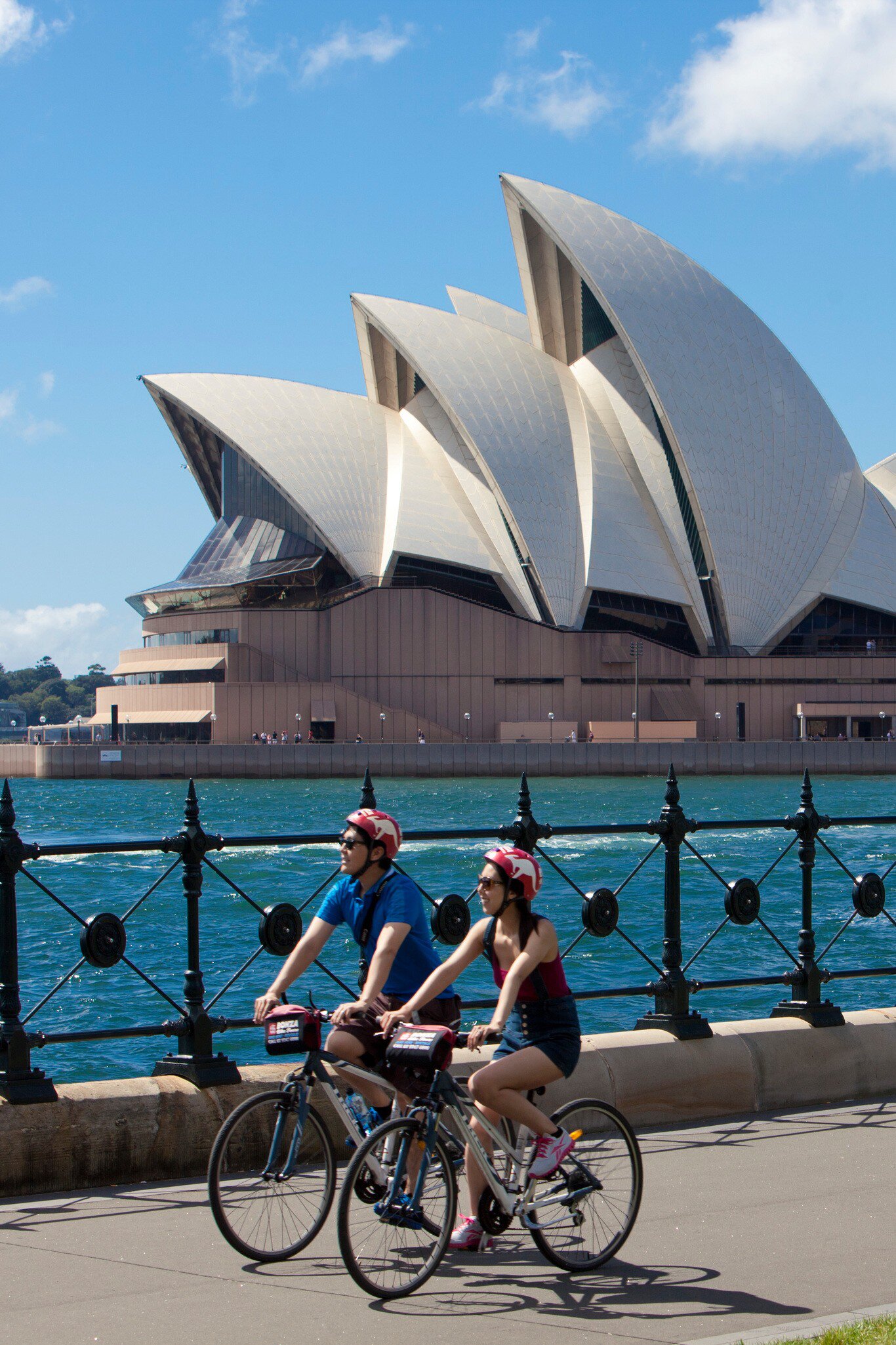 Two bikers biking past the Sydney Opera House as part of Bonza Bike Tours in Sydney, Australia.
