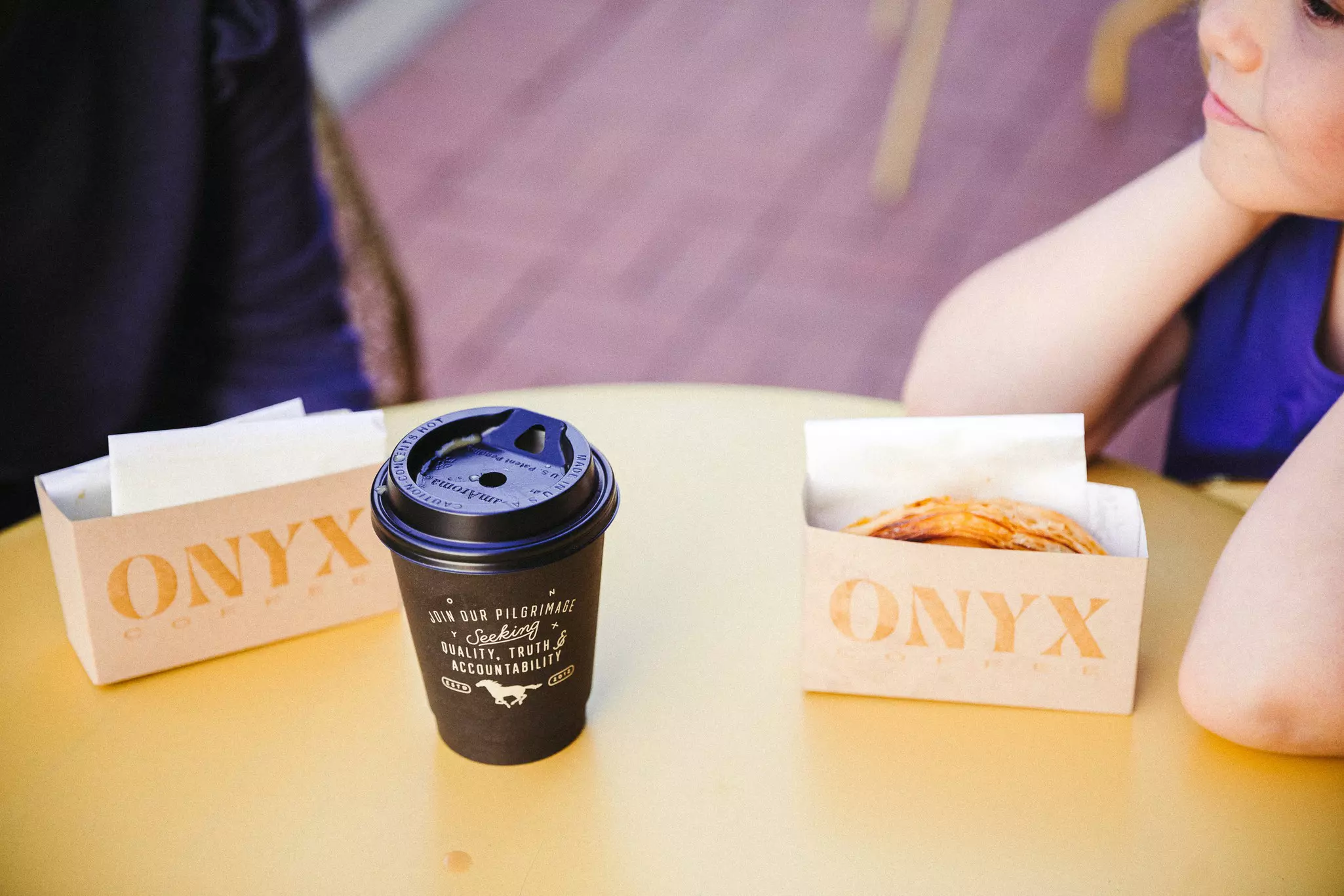 Two people sitting at a table with coffee and pastries.