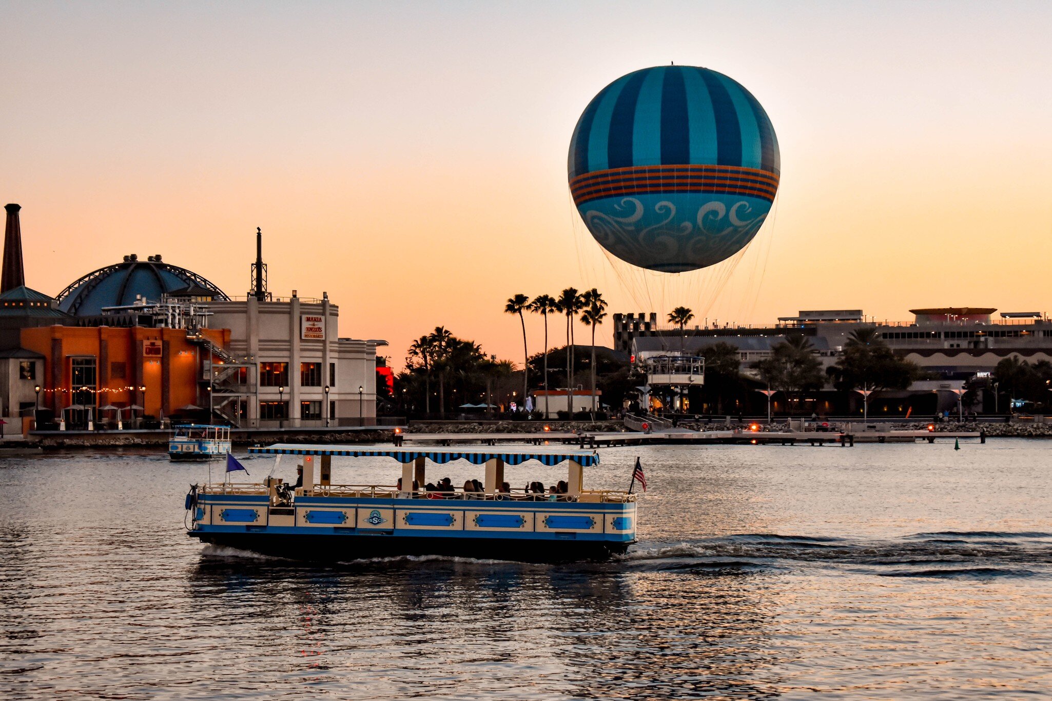Orlando, Florida. January 11, 2019 Panoramic view  of Disney Springs and water taxi on colorful sunset background at Lake Buena Vista area  (1)  License Type: media  Download Time: 2021-02-25T18:03:39.000Z  User: AHoward_lonelyplanet  Is Editorial: Yes  purchase_order:   