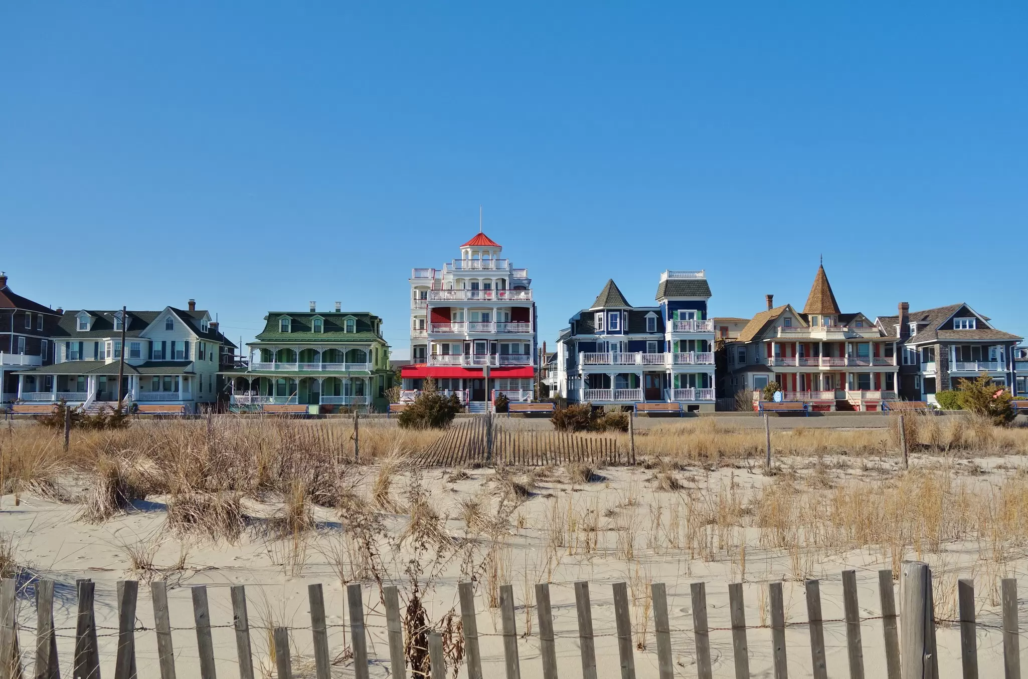 Colorful historic Victorian houses line the beachfront in Cape May, at the southern tip of Cape May Peninsula in New Jersey where the Delaware Bay and Atlantic Ocean meet. 