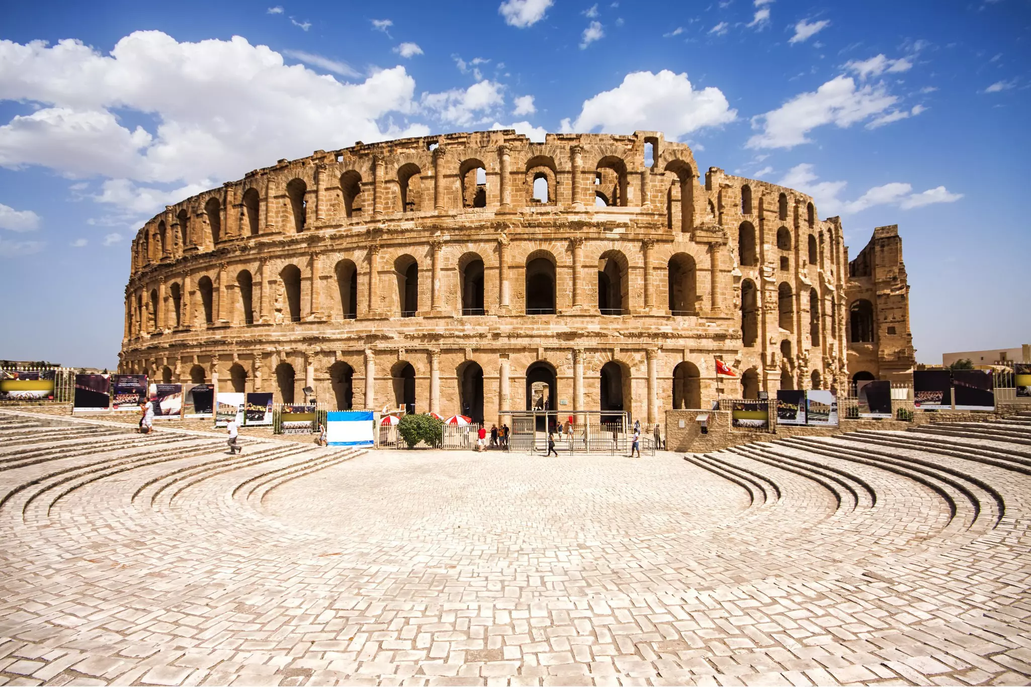 The exterior of a large colosseum with signs of degradation around the top tier.