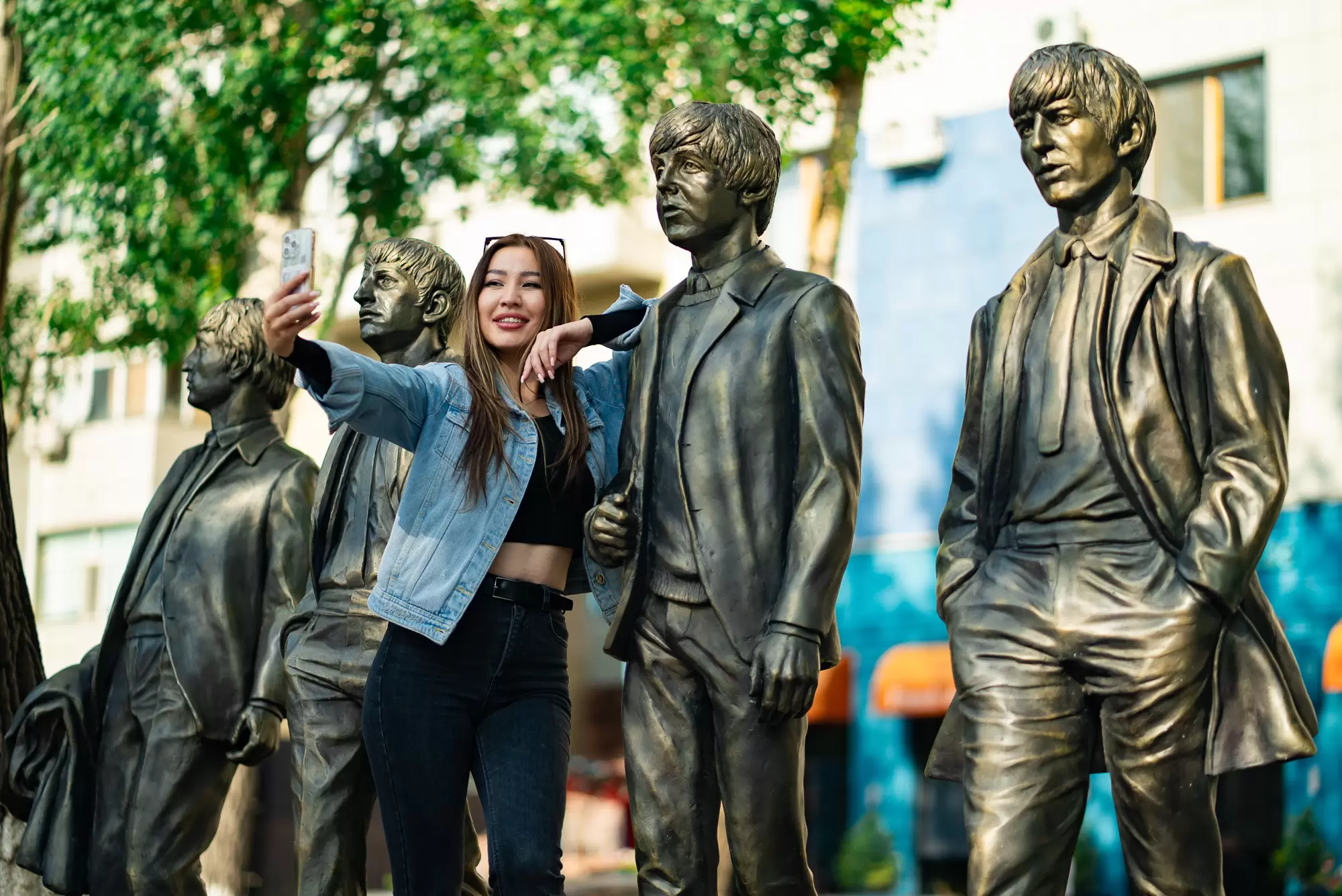 A young woman taking a selfie at the Beatles statue on Arbat in Astana, Kazakhstan.