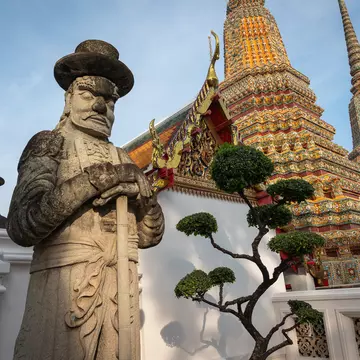 A statue in front of a temple complex.