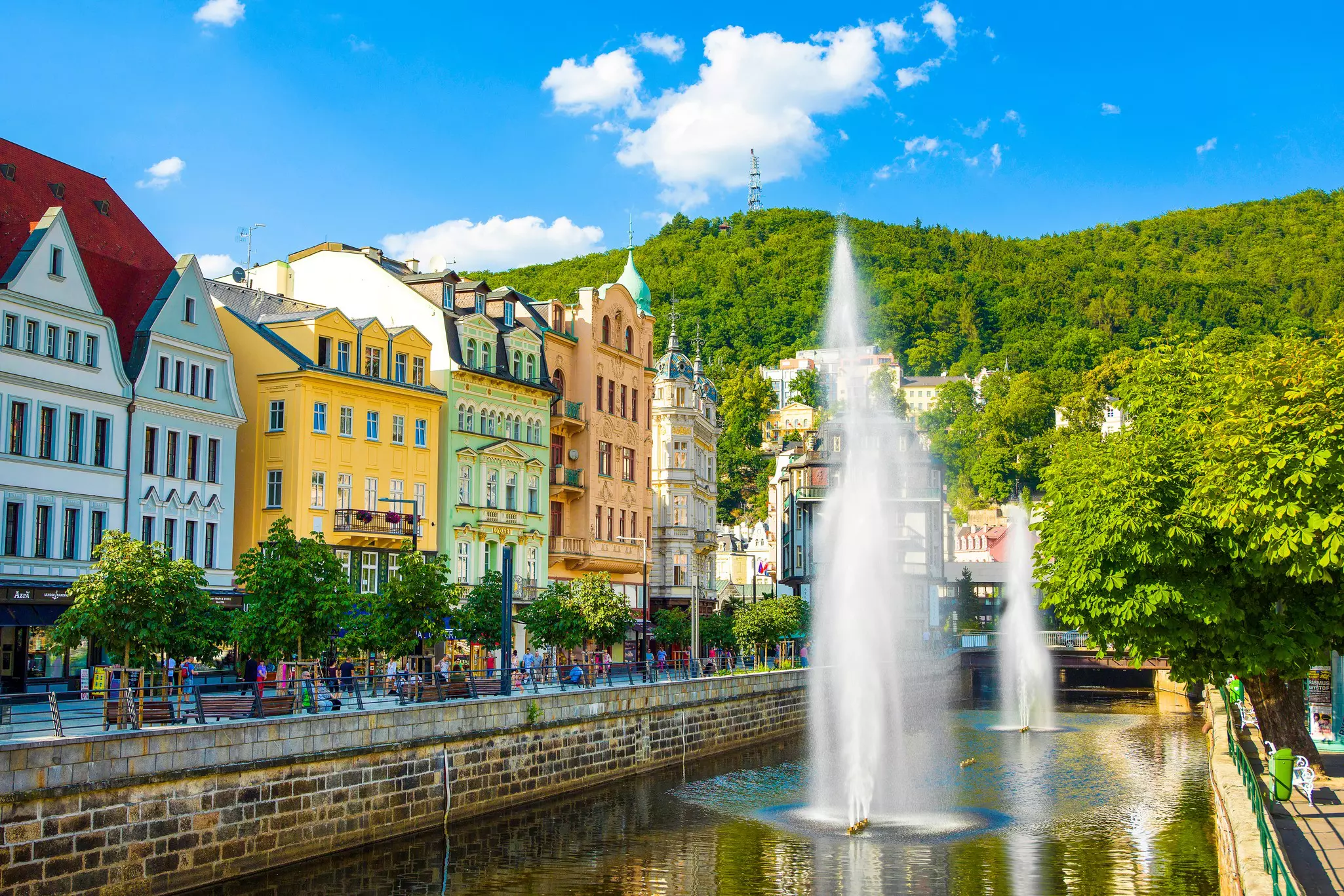 A fountain beside pastel-painted buildings on a sunny day