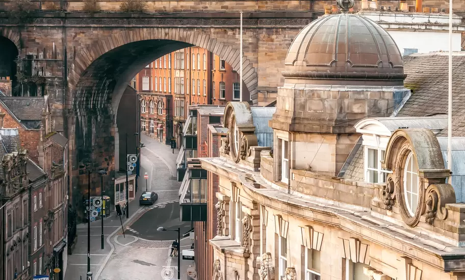 The Side street in Newcastle-upon-Tyne passing under a stone railway viaduct arch, with a domed sandstone building in front