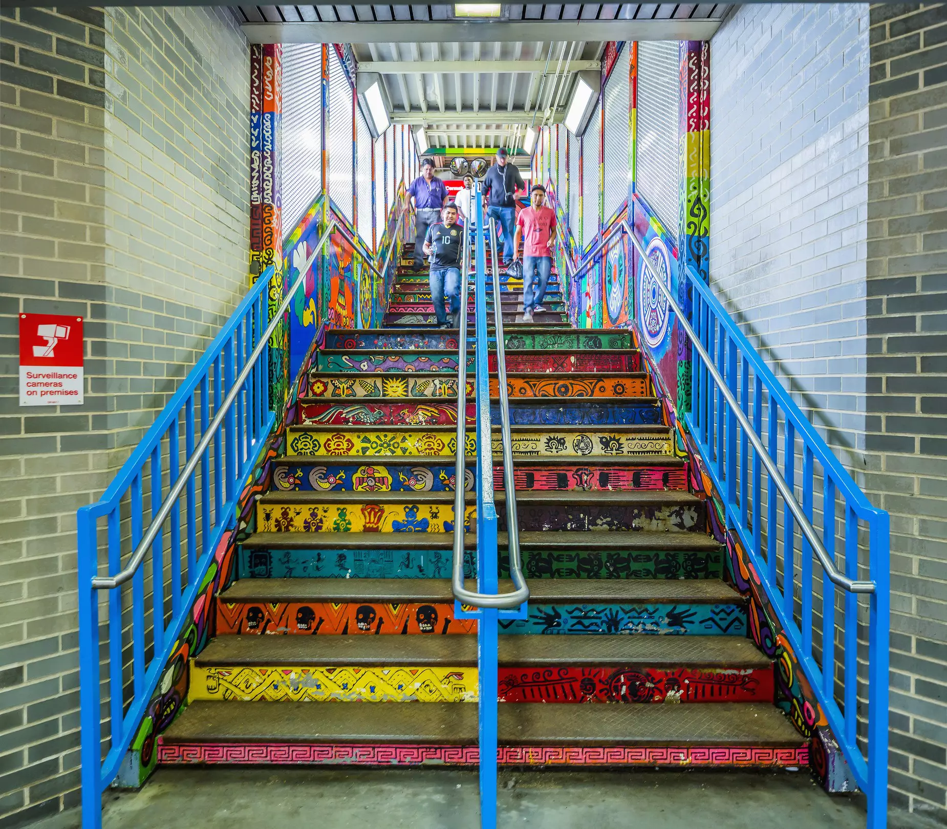 The exit steps of a metro station covered in brightly colored street art