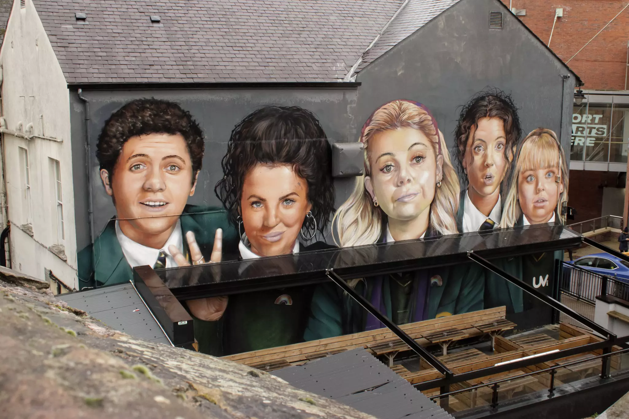 A mural of five faces painted on the side of a building.