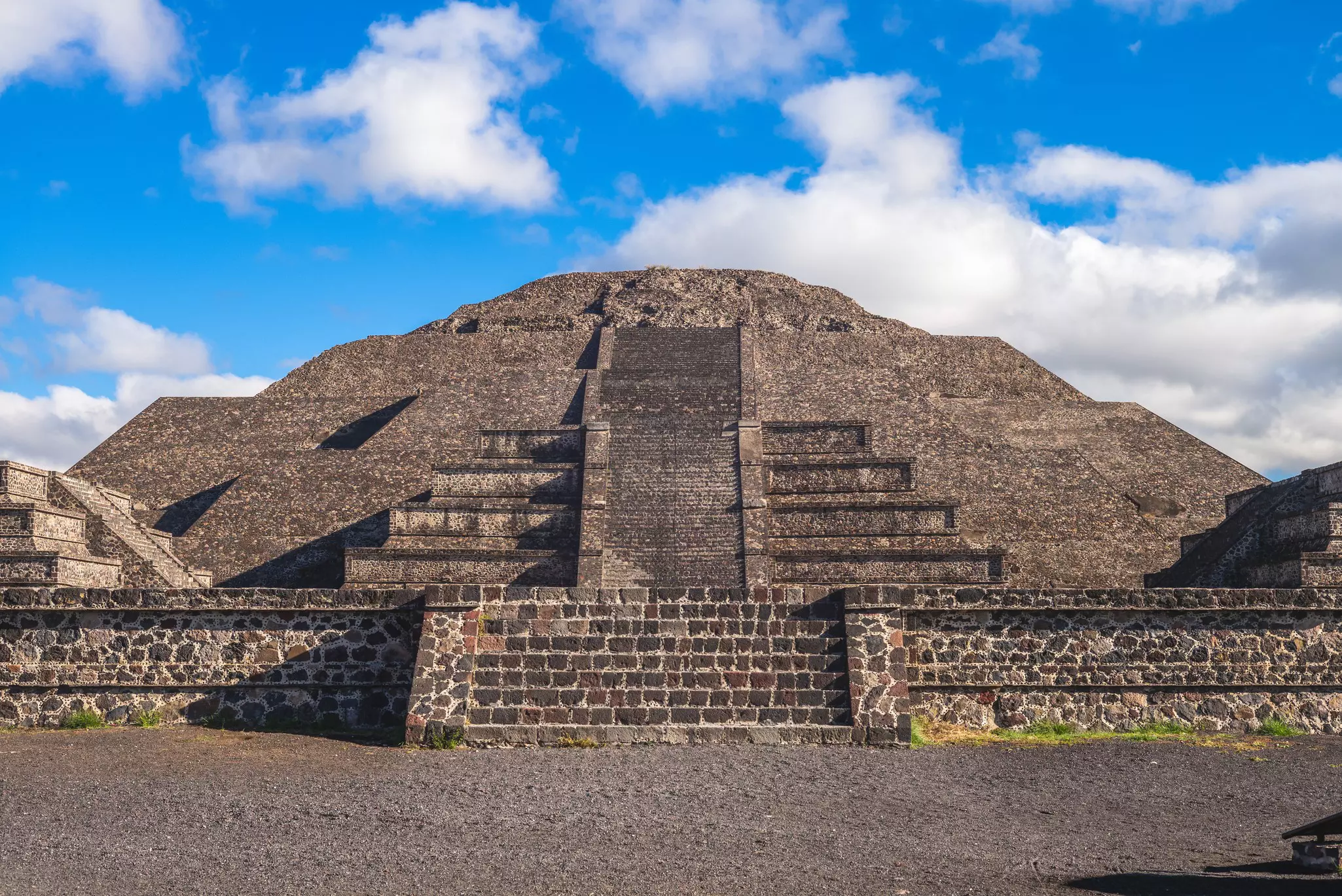 A stone pyramid at Teotihuacán with narrow steps leading to the top on a sunny day.