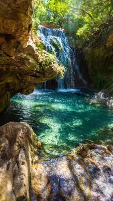 Waterfall of Akchour, Talassemtane National Park, Morocco with dappled sunlight on rocks in the foreground