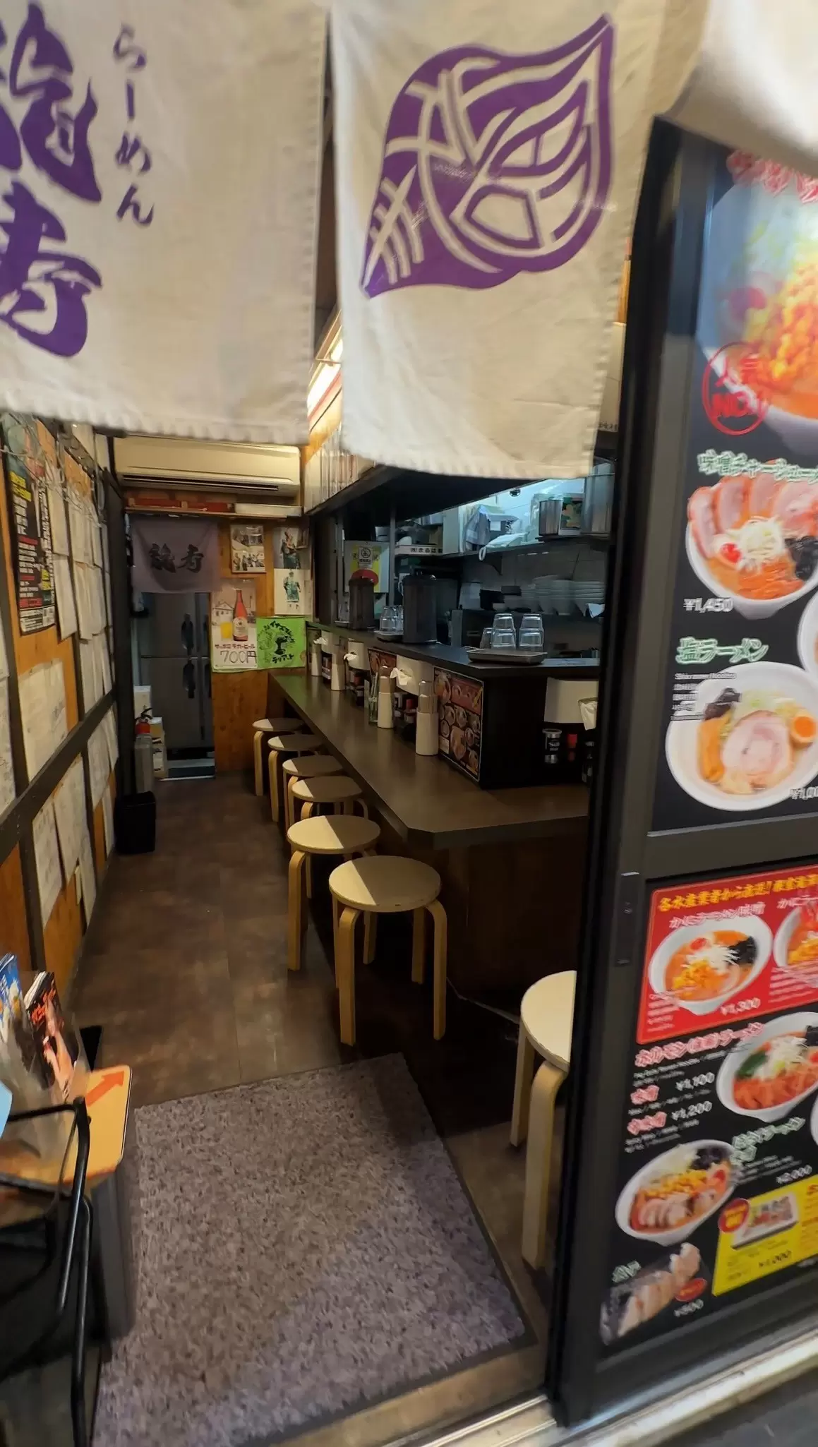 Six stools lined up at an empty counter in a rāmen shop; Ganso Ramen Yokocho, Sapporo