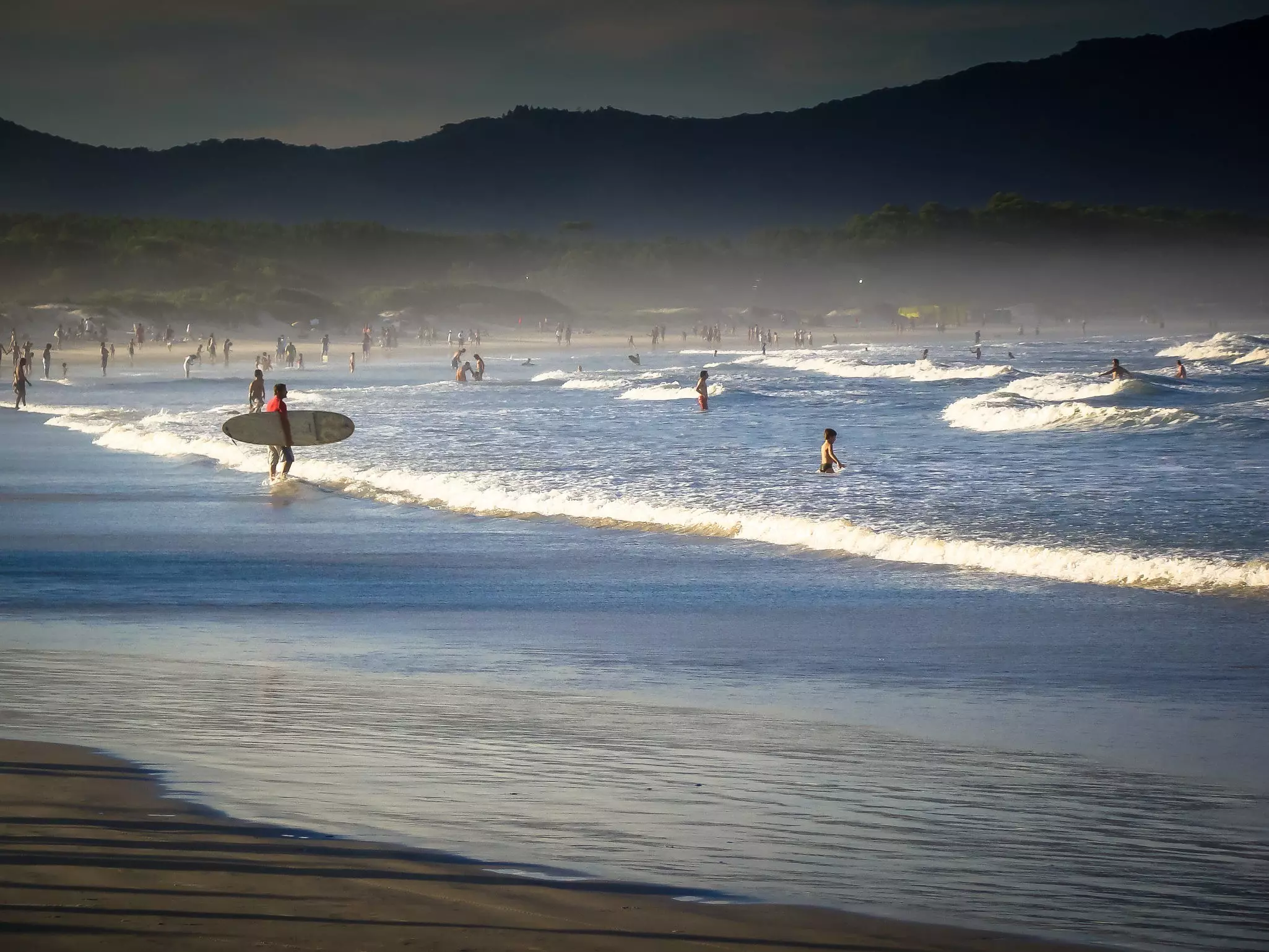 Surfers and swimmers at Barra da Lagoa beach in the late afternoon in Florianópolis, Brazil