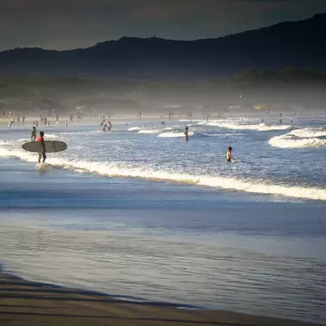 Surfers and swimmers at Barra da Lagoa beach in the late afternoon in Florianópolis, Brazil