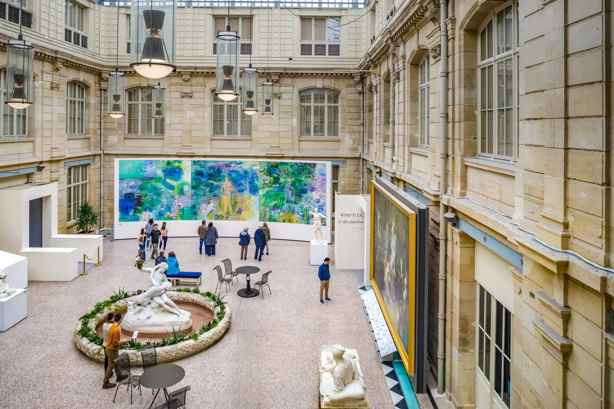 People gather around a huge painting within the courtyard of a museum