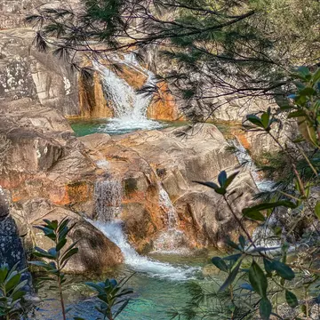 A multilevel waterfall with pools of water in rock.