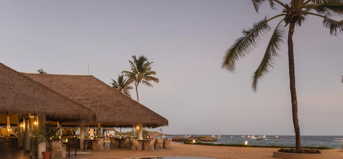 Two low pavilions by a pool at dusk.