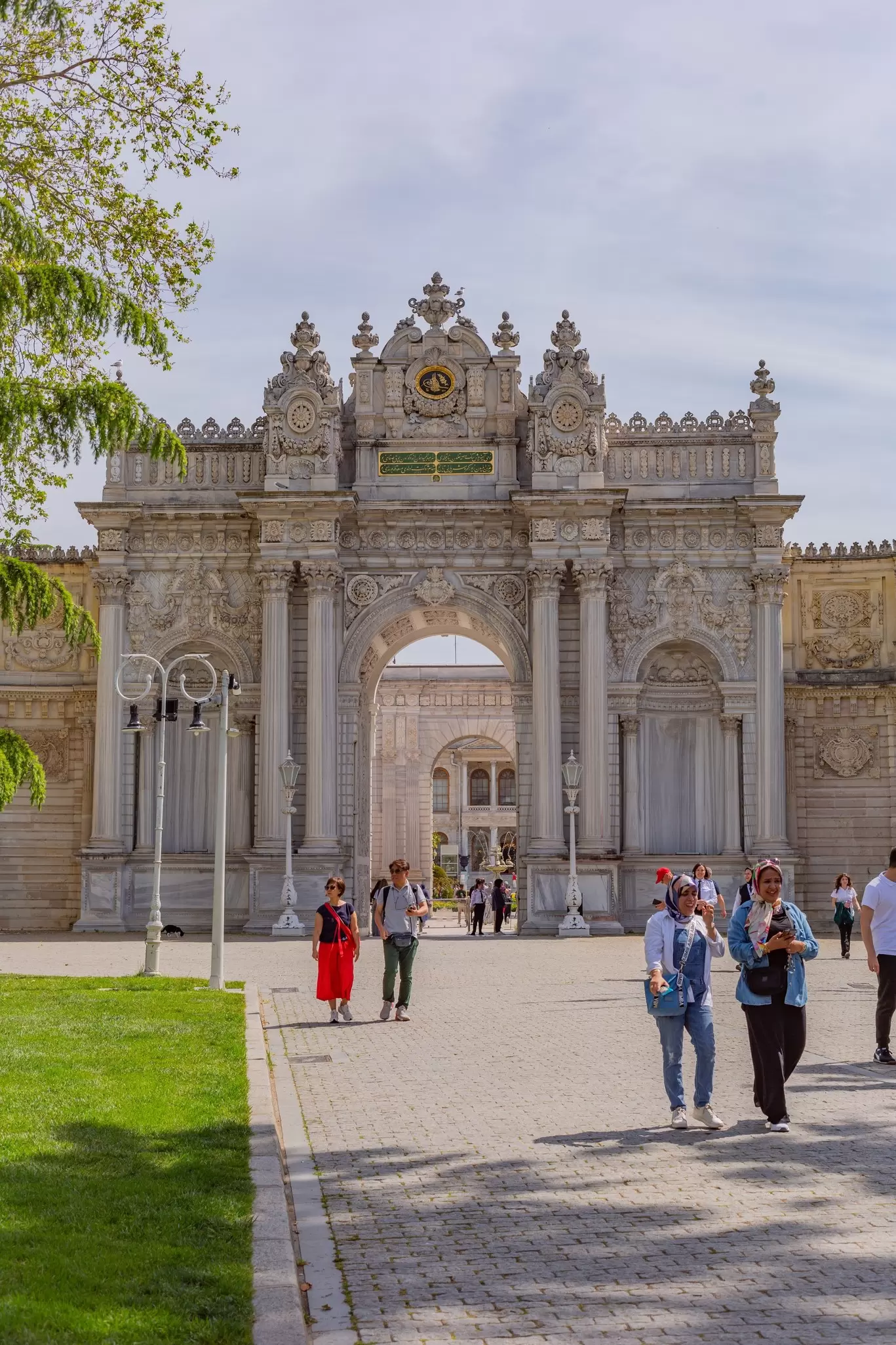 People walk away from an ornate archway at a palace complex.