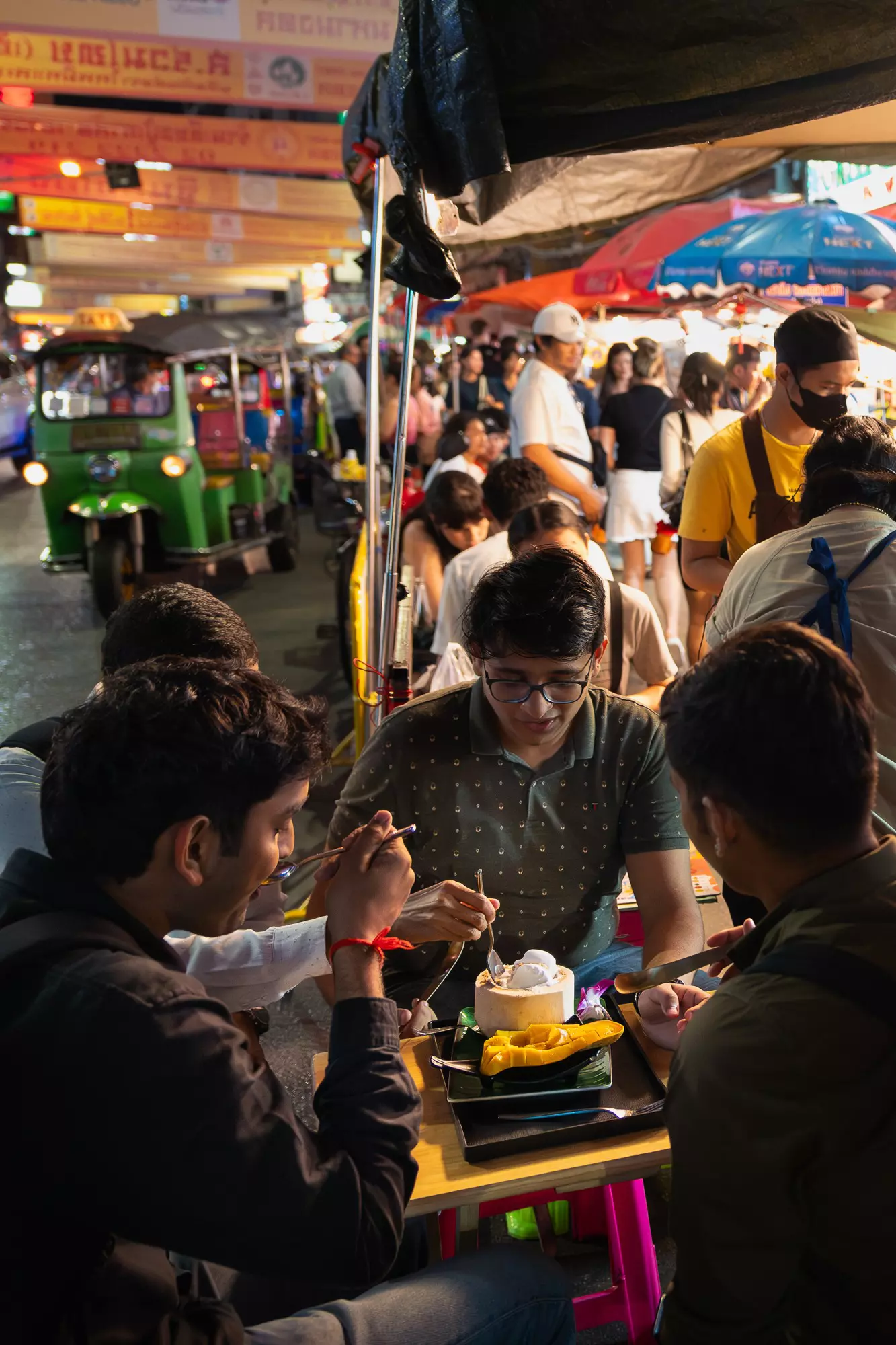 People eating street food at a streetside stall at night in Yaowarat, the center of Bangkok's Chinatown. 