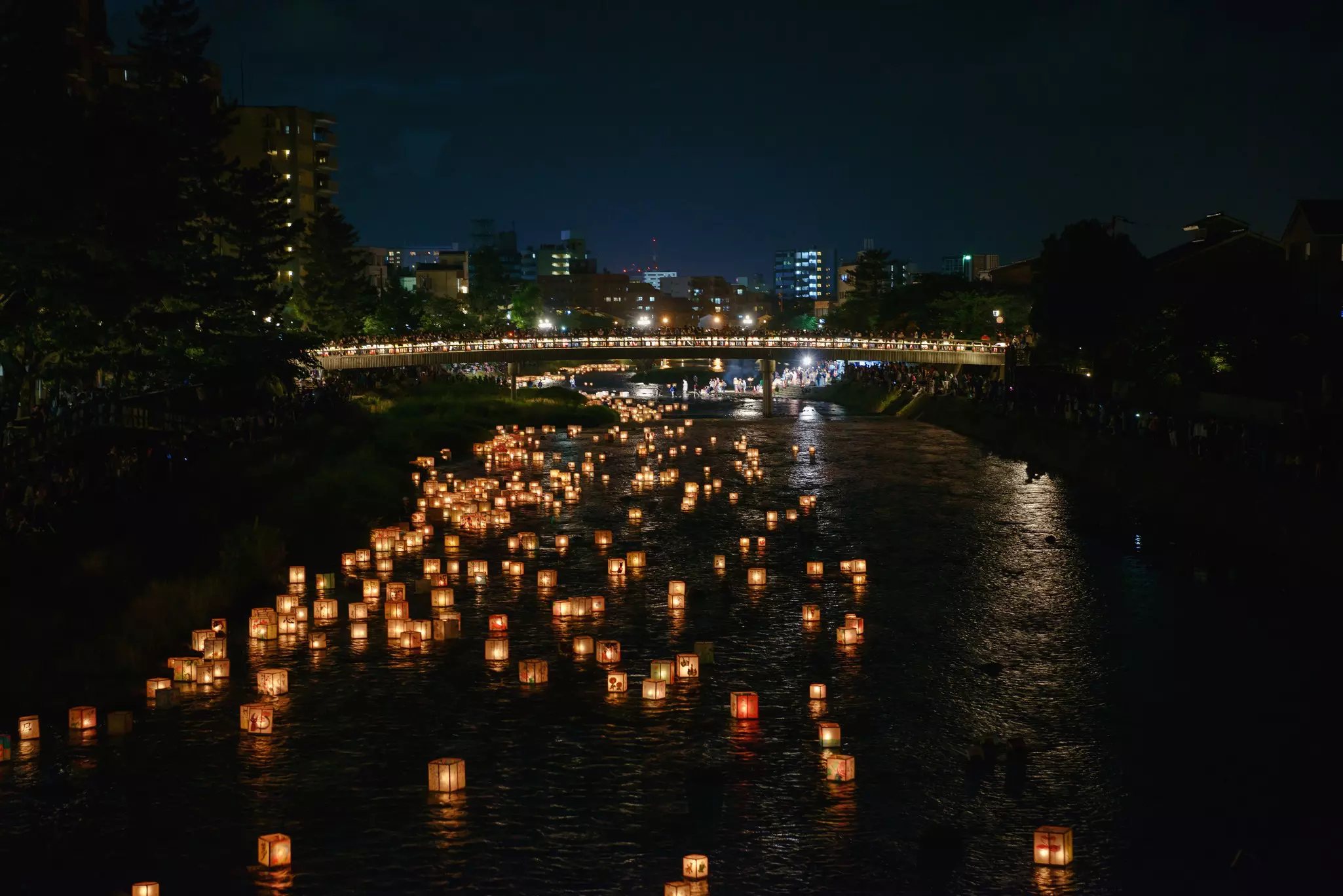 A scene of floating lanterns at night on the river during Hyakumangoku Festival in Kanazawa, Japan
