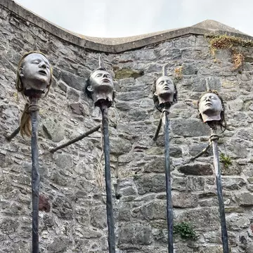 Elizabeth Fort in the centre of the Irish city of Cork, Ireland.  A sculpture of four men's heads, tethered to a brick wall.