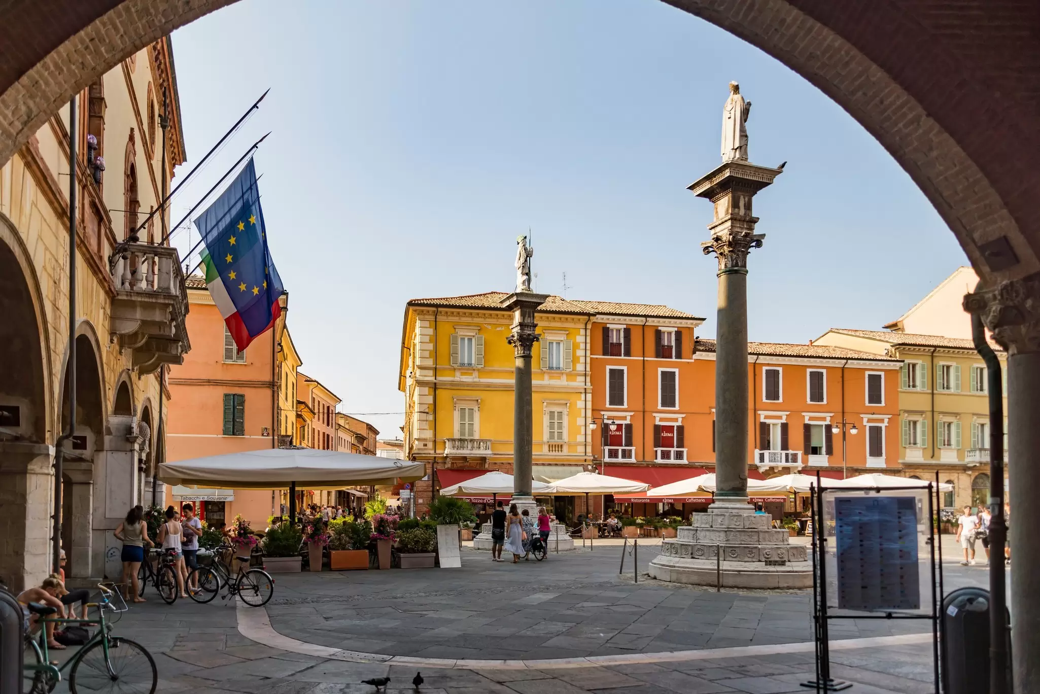 A city square where people are relaxing on a restaurant terrace